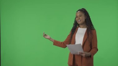 TV Hava Durumu Programı. Haber spikeri stüdyoda yeşil ekranın arkasında duruyor. Afrikalı Amerikalı kadın meteorolog yeşil ekranı işaret ediyor. Reklam alanı, çalışma alanı taklidi
