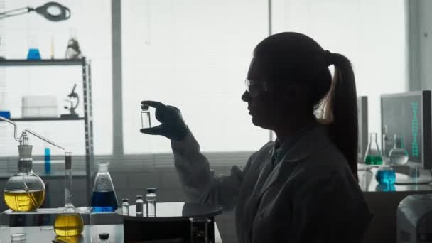研究和开发疫苗 一个拿着玻璃瓶的女科学家的黑暗轮廓 — 图库视频影像