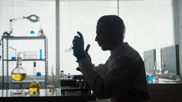 医学科学实验室一名男性研究人员将样本应用到玻璃滑块上 玻璃滑块是一种使用吸管的微型制剂 实验室显微镜前一位男性科学家的黑暗轮廓 — 图库照片