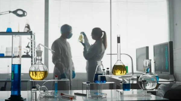 现代医学研究实验室 两位科学家一起分析了一个在艾伦迈耶瓶中的植物样本 讨论了结果 模糊的背景 高级医学实验室 — 图库照片