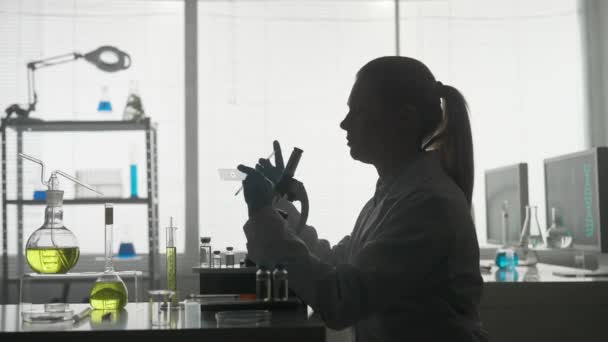 医学科学实验室一个在显微镜下观察的女科学家的暗影侧视图 对一个实验样本进行了近距离分析 雄心勃勃的生物技术专家 — 图库视频影像