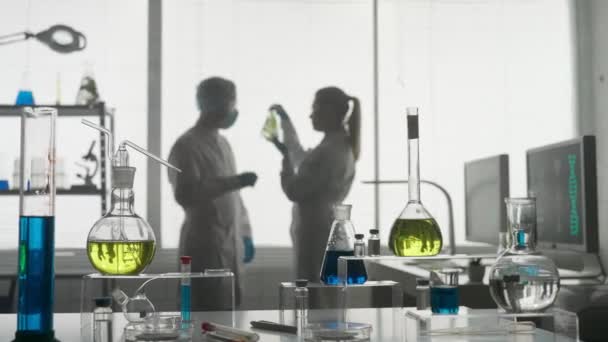 现代医学研究实验室 两位科学家一起分析了一个在艾伦迈耶瓶中的植物样本 讨论了结果 模糊的背景 高级医学实验室 — 图库视频影像