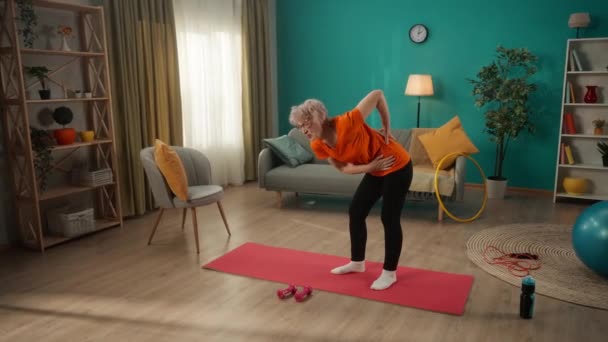 与年龄有关的 肌肉背痛 一位老年妇女在运动时弯腰抱住哑铃 剧痛地抓着她的背 一个退休的女人挺起腰背 痛苦不堪 — 图库视频影像
