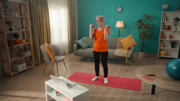 Eine Ältere Frau Turnt Mit Hanteln Vor Einem Laptop Wohnzimmer — Stockvideo