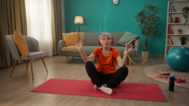 Kırmızı Kulaklıklı Yaşlı Bir Kadın Oturma Odasında Bir Spor Paspasın — Stok video