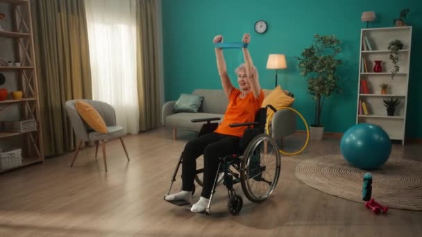 Μια Ηλικιωμένη Γυναίκα Αναπηρική Καρέκλα Γυμνάζεται Ένα Αθλητικό Λάστιχο Στο — Αρχείο Βίντεο