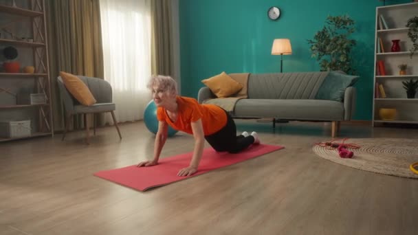 老年妇女在锻炼后做伸展运动 一位白发苍苍的妇女双膝跪下来 后缩骨盆 前伸胳膊 后仰着身子向前伸 — 图库视频影像