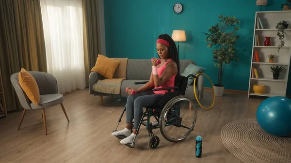 Tekerlekli Sandalyedeki Afrikalı Amerikalı Kadın Oturma Odasında Dambıllarıyla Egzersiz Yapıyor — Stok fotoğraf