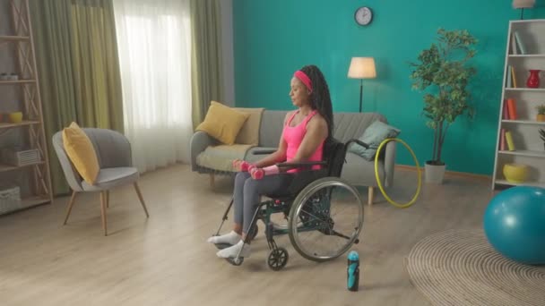 Tekerlekli Sandalyedeki Afrikalı Amerikalı Kadın Oturma Odasında Dambıllarıyla Egzersiz Yapıyor — Stok video