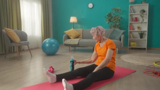 Starsza Kobieta Zmęczona Codziennym Treningu Siedzi Macie Gimnastycznej Salonie Kobieta — Wideo stockowe