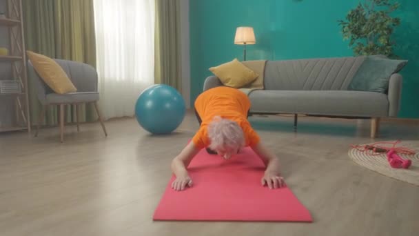 老年妇女在锻炼后做伸展运动 一个女人坐在她的膝上向前倾斜 把她的骨盆往后拉 把她的胳膊向前伸 然后向前弯腰 — 图库视频影像