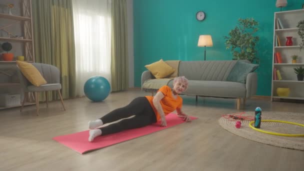 Μια Ηλικιωμένη Γυναίκα Ξαπλώνει Ένα Αθλητικό Χαλάκι Στο Πάτωμα Του — Αρχείο Βίντεο