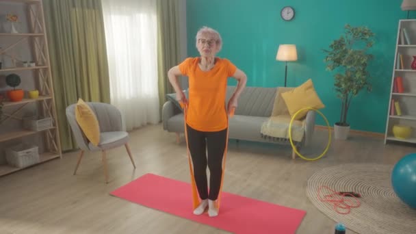 Eine Grauhaarige Rentnerin Trainiert Wohnzimmer Mit Einem Sport Gummiband Eine — Stockvideo
