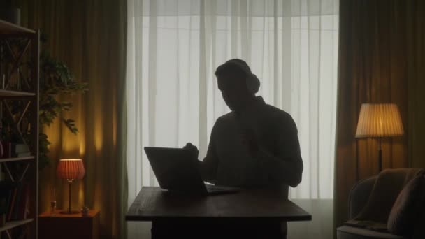 Siluet Gelap Seorang Pria Dengan Headphone Nirkabel Meja Depan Laptop — Stok Video