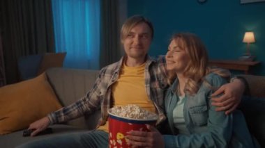 Genç romantik bir çift film izliyor ve patlamış mısır yiyor. Gülümseyen adam ve kadın oturma odasında rahat bir kanepede sarılıp dinleniyorlar, komedi filminin tadını çıkarıyorlar. Bir sevginin portresi