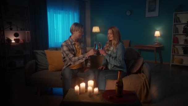 家庭でキャンドルライトによってロマンチックな夜 若いカップルのクリンクグラス シャンパンを飲み リビングルームのソファに座っています 若い男は手で女性を取り 彼女の目を調べる — ストック動画