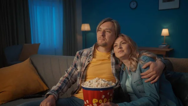 一对年轻夫妇正在看电影 吃爆米花 在客厅里舒服的沙发上拥抱和放松地微笑着 欣赏着一部喜剧电影 爱情的画像 — 图库照片