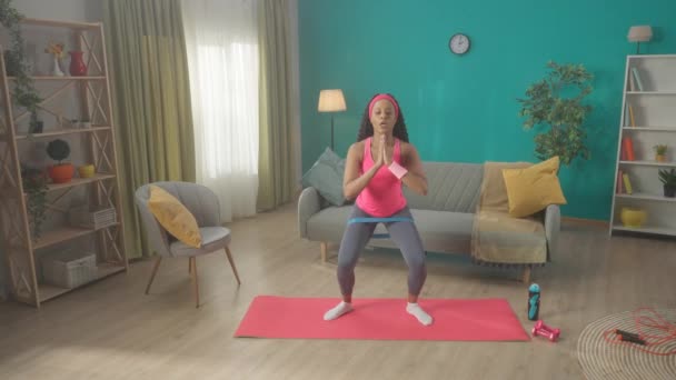 身穿粉色运动服头戴运动帽带的非洲裔美国妇女正在家里用橡皮筋进行训练 这个女人的确坐起来 走到旁边 健康和运动的生活方式 慢一点 — 图库视频影像