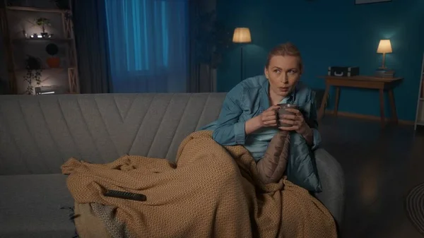 Молодая Женщина Лежит Диване Одеялом Прикрывающим Ноги Смотрит Телевизор Чашкой — стоковое фото