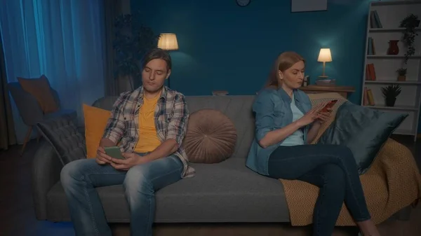 関係の問題 夫婦はソファの上に座り 背を向けている 男と女は互いを無視し それぞれが彼のスマートフォンで忙しい — ストック写真