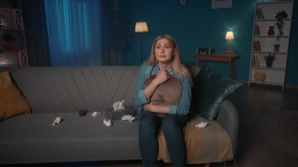 一个多愁善感的女人一边看一部戏剧性的 悲伤的电影 一边用纸巾擦干眼泪 一个女人晚上坐在沙发上 抱着孩子 抱着孩子 — 图库视频影像