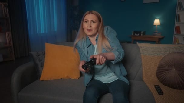 Горячая Эмоциональная Женщина Играет Консульскую Игру Игровым Контроллером Сидя Вечером — стоковое видео