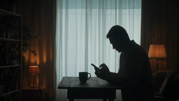 Bir Adam Elinde Telefonla Bir Masada Duruyor Yanında Bir Fincan — Stok fotoğraf
