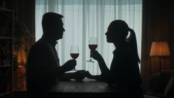 这对夫妇手牵着手 烛光下喝着红酒度过了一个晚上 坐在桌旁客厅里的一个男人和一个女人的黑暗轮廓 浪漫的夜晚 — 图库照片