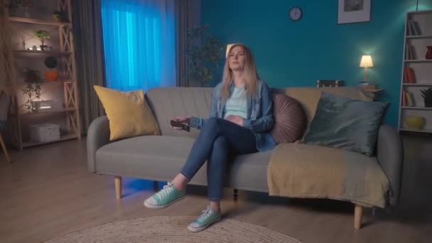Woman Sits Couch Turns Remote Control Woman Adjusts Brightness Lighting — Stock Video