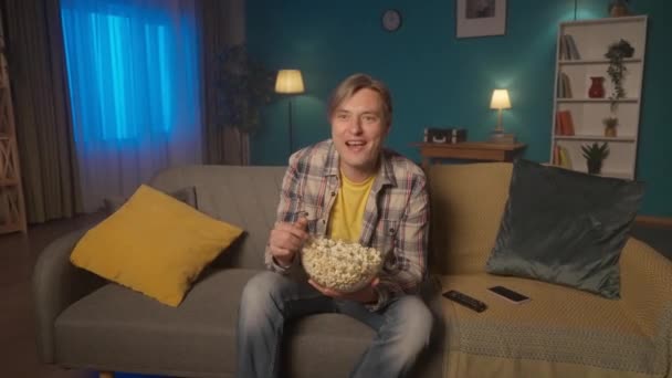Wieczorem Mężczyzna Siedzi Kanapie Popcorn Ogląda Telewizję Mężczyzna Ogląda Komedię — Wideo stockowe