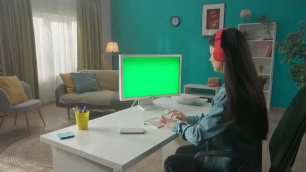 Asijská Žena Poslouchá Hudbu Sluchátky Zatímco Pracuje Počítače Zelenou Obrazovkou — Stock video