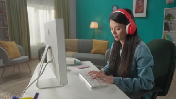 Μια Γυναίκα Κόκκινα Ασύρματα Ακουστικά Δουλεύει Υπολογιστή Μια Νεαρή Γυναίκα — Αρχείο Βίντεο