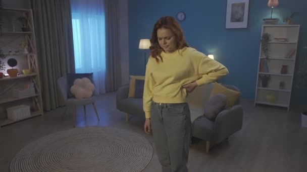 Redhaired Woman Suffers Back Pain While Standing Living Room Woman — Stockvideo