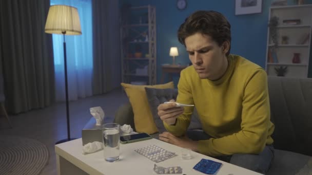 Man Measures Temperature Thermometer Sitting Home Couch Front Table Medicines — Αρχείο Βίντεο