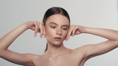 Çekici esmer bir kadın modelin portresi. Bir kadının kameraya bakarken, yüzüne dokunurken, elmacık kemikleri bölgesindeki pürüzsüz deriyi yakından çek. Güzellik derisi reklam konsepti.