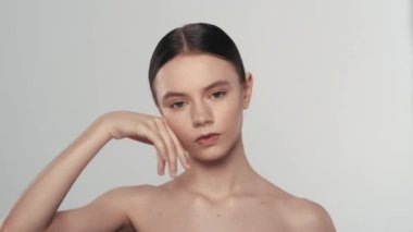 Çekici esmer bir kadın modelin portresi. Bir kadının kameraya bakarken, yüzüne dokunurken, yanaklarındaki pürüzsüz deriyi yakından çek. Güzellik derisi reklam konsepti.