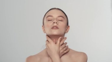 Beyaz kadın modelin çekici portresi. Güzel bir kadının kameraya bakıp, pürüzsüz tenine ve yüzüne dokunuşunu yakından çek. Güzellik derisi reklam konsepti.