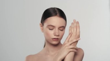 Çekici beyaz esmer modelin portresi. Bir kadının kameraya bakıp, eline, pürüzsüz tenine dokunuşunu yakından çek. Güzellik derisi reklam konsepti.