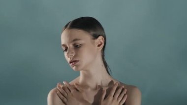 Çekici beyaz esmer modelin portresi. Kameraya bakan, omuzlarına dokunan pürüzsüz cildine dokunan bir kadını yakından çek. Karmaşık vücut bakımı güzellik reklam konsepti.