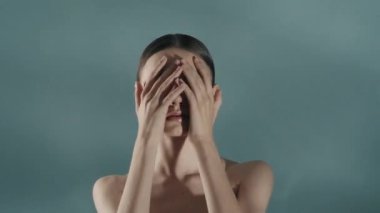 Güzel bir kadın modelin portresi. Kameraya bakan bir kadının yakın plan görüntüsü. Yüzüne, saçına ve boynuna dokunuyor. Ferahlatıcı görünüş. Kompleks cilt reklam kavramı.