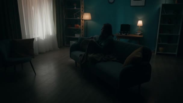 在黑暗的房间里 一个孤独的年轻女人坐在沙发上 一个女人绝望地思考着个人问题 正在经历一场危机 哭泣着 日日夜夜的变化 时间的转移 — 图库视频影像