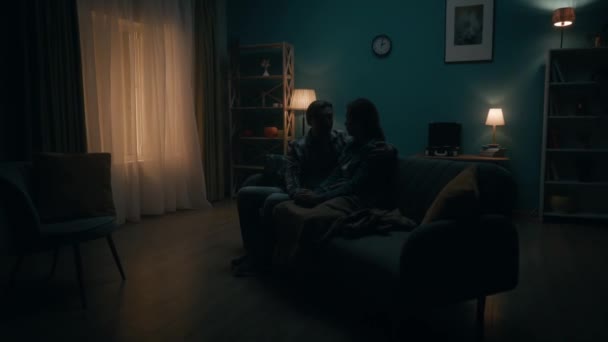在黑暗的房间里 一对夫妇正坐在沙发上 男人倾听女人的声音 牵着她的手 拥抱她 对夫妻的支持 共同解决问题 和解与理解 — 图库视频影像