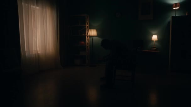 Зруйнований Самотній Чоловік Сидить Головою Вклонившись Стілець Посеред Кімнати Пітьмі — стокове відео