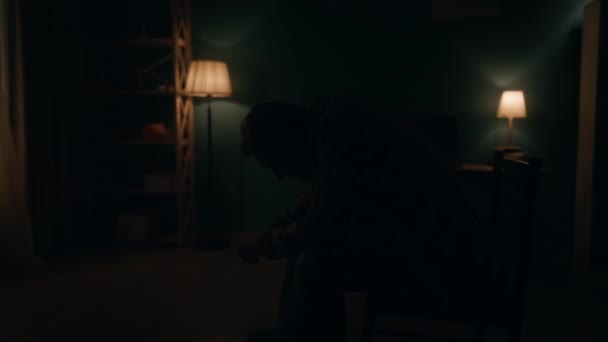 悲惨な孤独な男が 暗闇の中で部屋の真ん中に椅子に腰掛けられた頭で座っている 夜が明けると 男は頭を上げて窓から光を見る トランシエンス — ストック動画