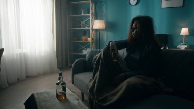 Dağınık bir kadın elinde bardakla, masada bir şişe alkolle oturuyor. Bir kadın alkol yardımıyla sorunlardan kurtulur. Alkol bağımlılığı tedavisi. Ruh sağlığı konsepti