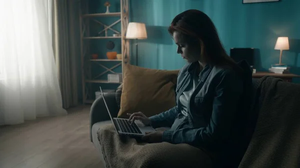 在笔记本电脑上工作的疲惫女人靠得很近 上网学习 坐在黑暗的房间里 灯光从窗户射进来 上网成瘾 一个人工作很辛苦 精神健康的概念 — 图库照片