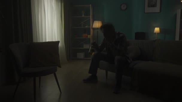 Hombre Devastado Sienta Una Habitación Oscuridad Con Una Botella Alcohol — Vídeo de stock