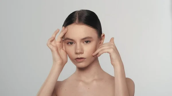 一个有着自然妆容的黑发女模特的肖像 一个手臂向上的女人的近照 触摸她的脸在颧骨区域 看着相机 美容美发广告概念 — 图库照片