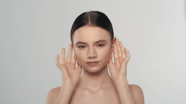 一个有着自然妆容的黑发女模特的肖像 一个女人的近照 触摸她的脸在颧骨区域 看着相机 美容广告概念 — 图库照片