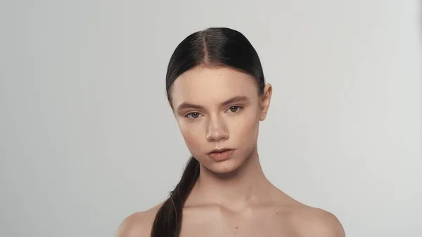 一个年轻美丽的女性模型的肖像 有着柔软的皮肤 自然的妆容和长长的马尾辫 一个女人看着摄像机的近照 美体护理广告概念 — 图库照片
